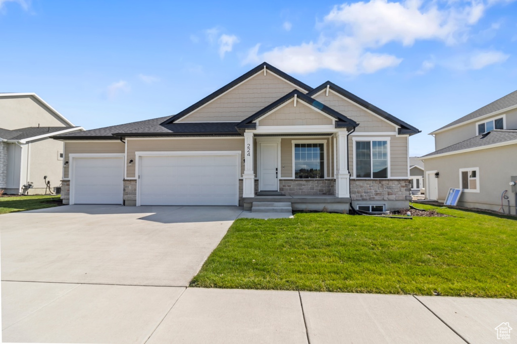 Craftsman house featuring concrete driveway, stone siding, covered porch, a front yard, and an attached garage