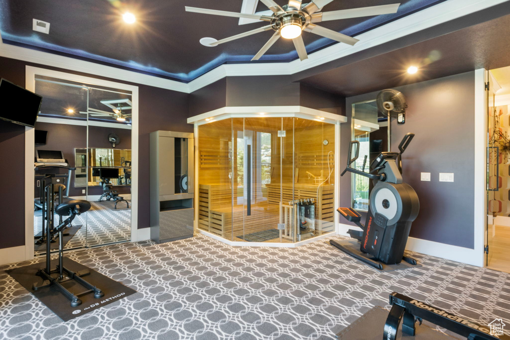 Workout room with ceiling fan, carpet, ornamental molding, and a towering ceiling