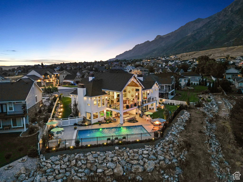 Back house at dusk featuring a fenced in pool, a patio area, and a mountain view