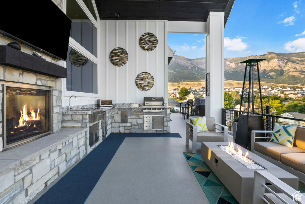 View of patio / terrace with a mountain view, an outdoor living space with a fireplace, and exterior kitchen