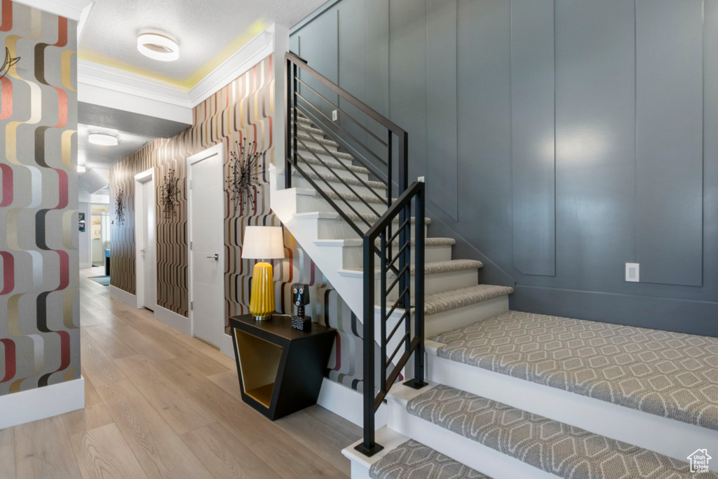 Stairway with wood-type flooring and crown molding