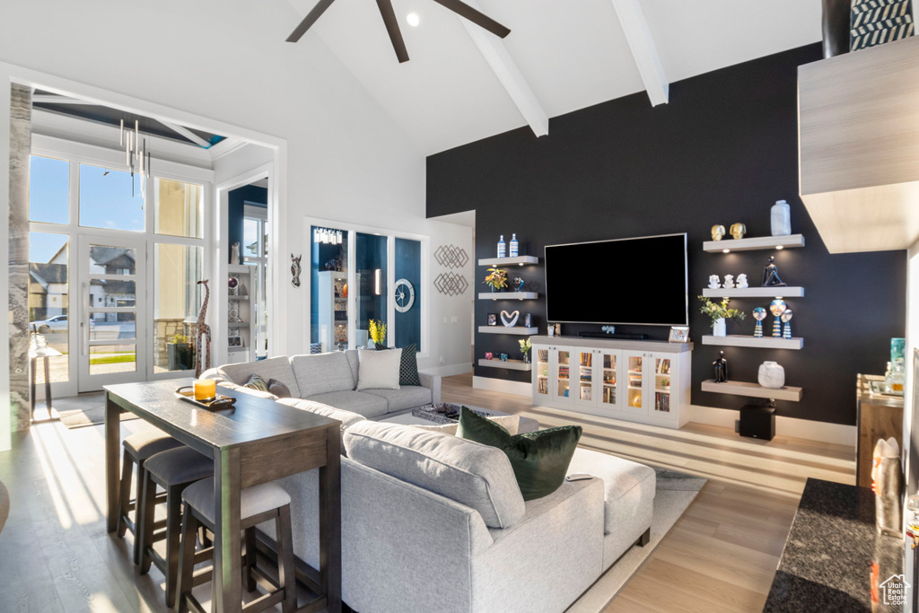 Living room with ceiling fan, beamed ceiling, light hardwood / wood-style flooring, and high vaulted ceiling