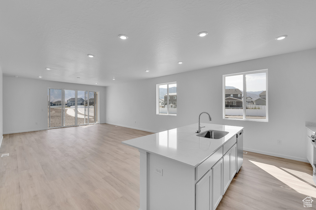 Kitchen featuring a sink, light countertops, light wood finished floors, recessed lighting, and baseboards