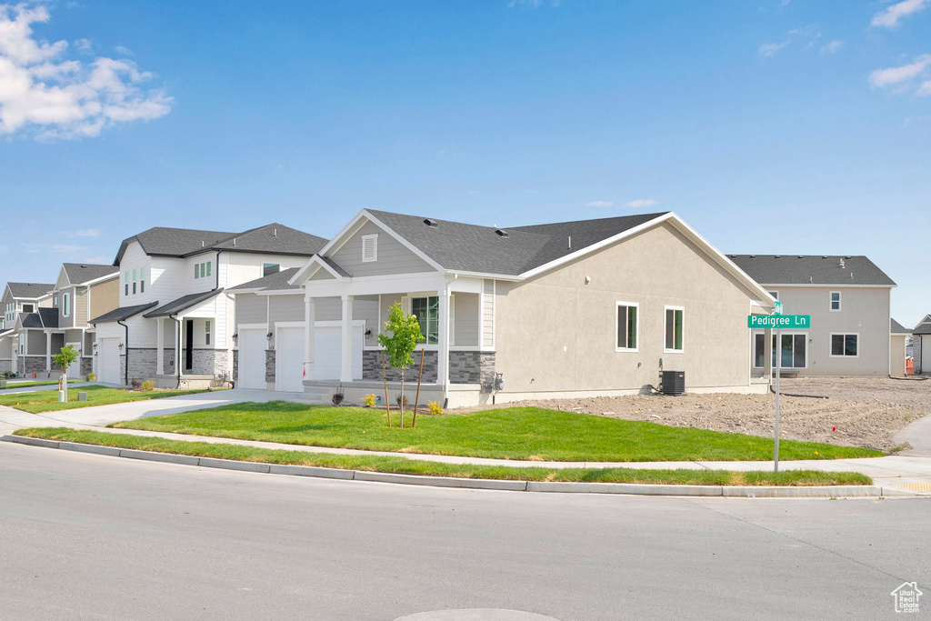 View of front facade featuring a residential view, driveway, a garage, stone siding, and cooling unit