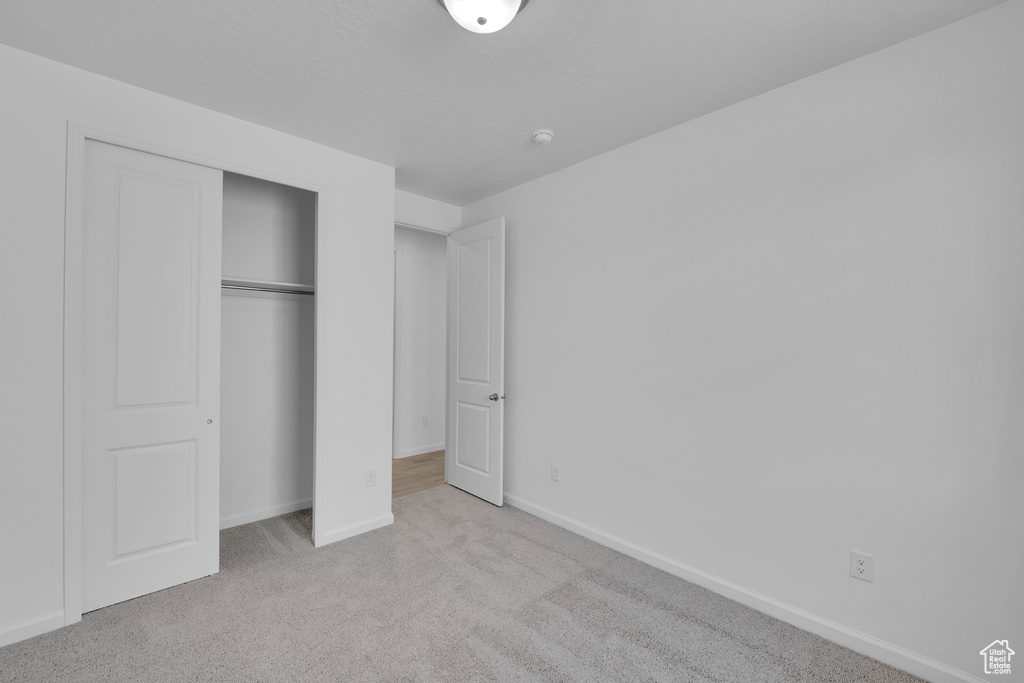 Unfurnished bedroom featuring carpet, baseboards, and a closet