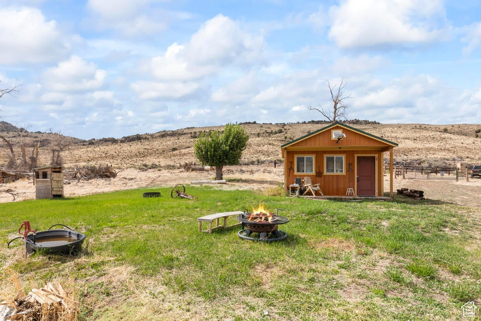 View of yard with a fire pit, an outbuilding, and a rural view