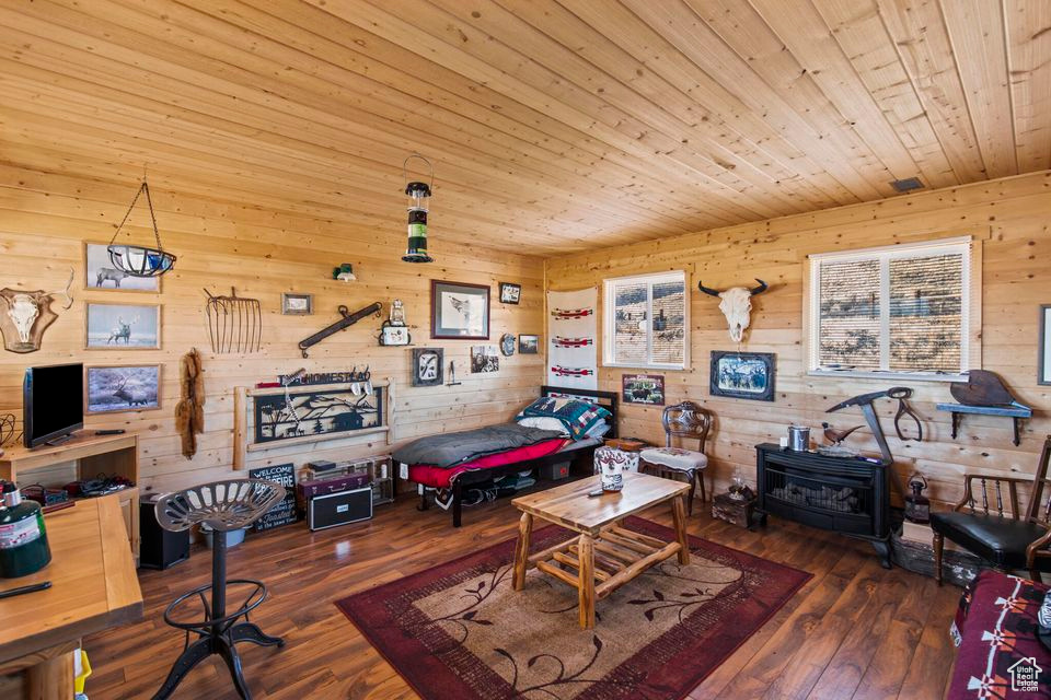 Rec room featuring a wood stove, wood ceiling, wood walls, and hardwood / wood-style floors