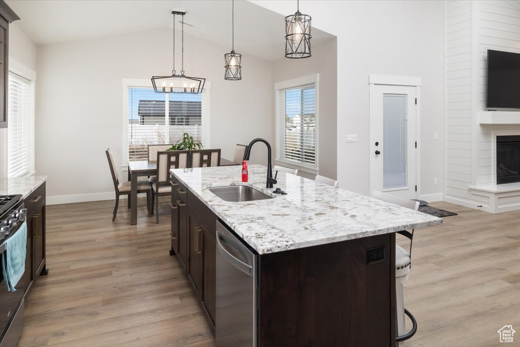 Kitchen with a kitchen island with sink, dishwasher, dark brown cabinetry, and sink