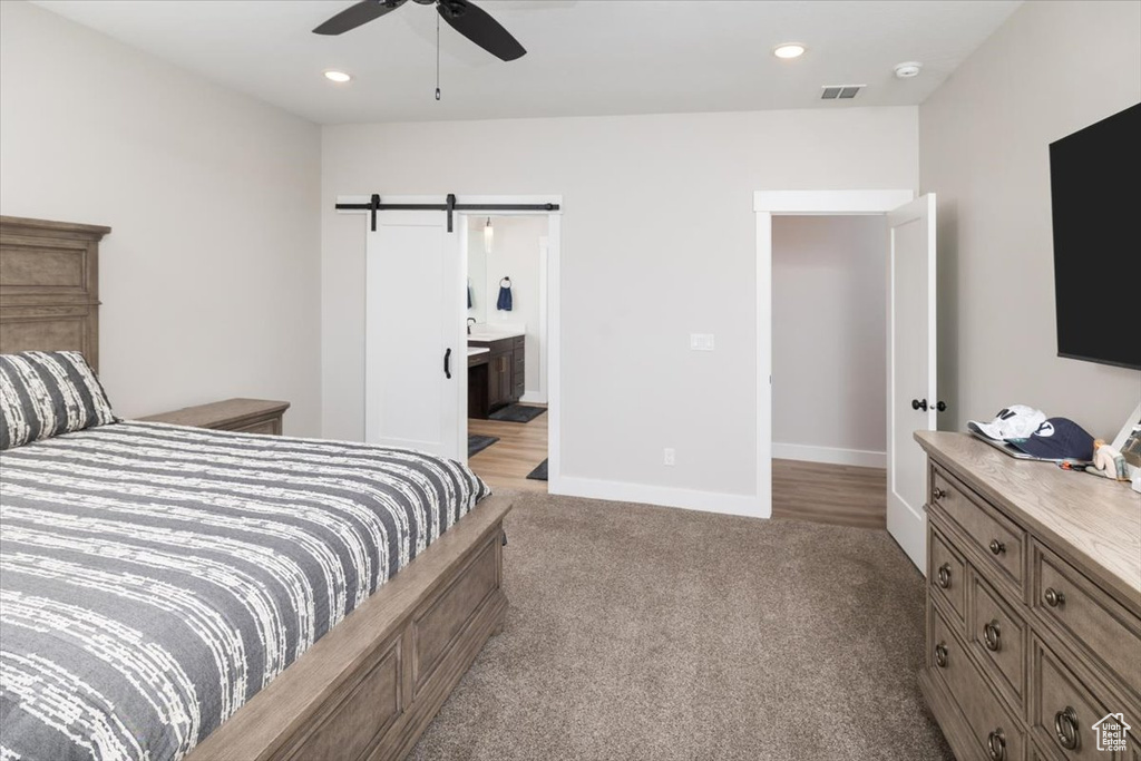 Carpeted bedroom with ceiling fan, ensuite bathroom, and a barn door