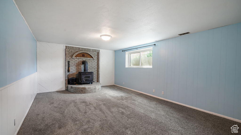 Unfurnished living room featuring a wood stove and carpet