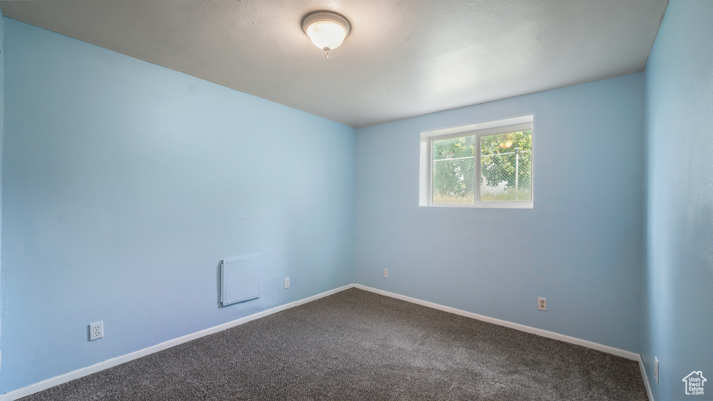 Unfurnished room featuring dark colored carpet and baseboards