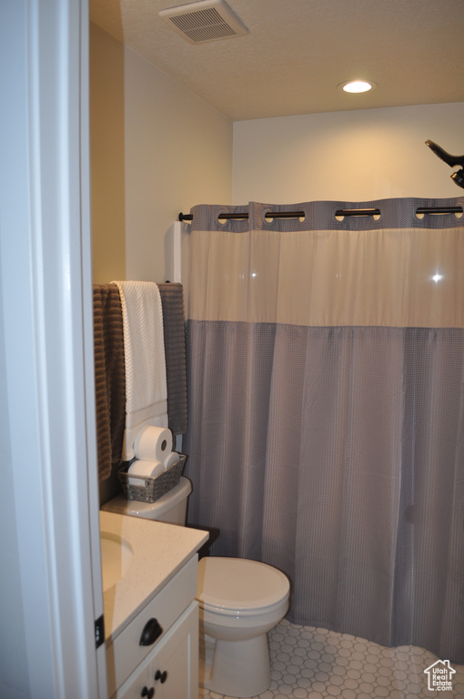 Bathroom featuring toilet, tile patterned flooring, vanity, and curtained shower