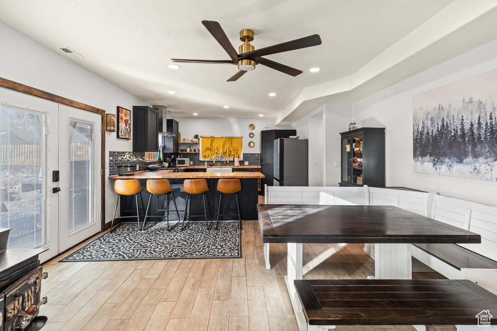 Kitchen with french doors, stainless steel fridge, kitchen peninsula, light wood-type flooring, and ceiling fan