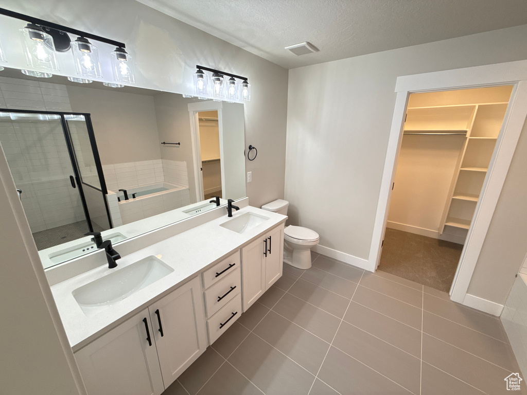 Full bathroom featuring a textured ceiling, tile patterned flooring, vanity, toilet, and plus walk in shower