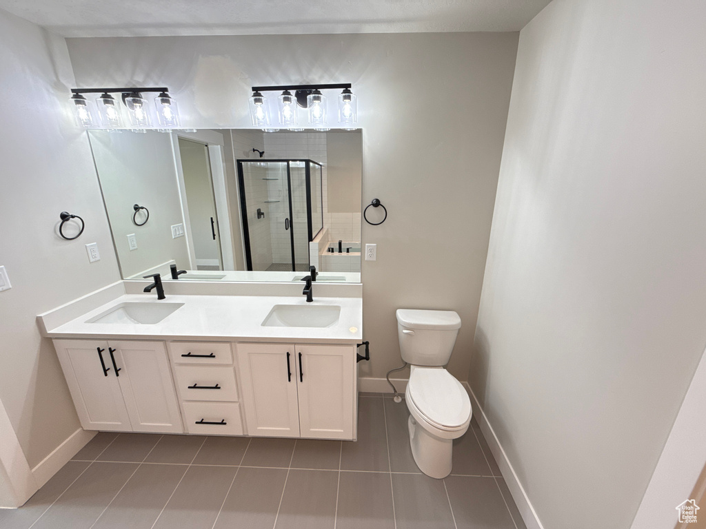 Bathroom featuring a shower with shower door, tile patterned floors, vanity, and toilet