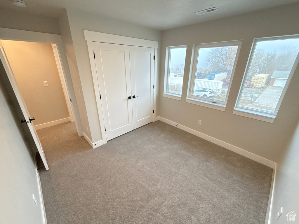 Unfurnished bedroom with light colored carpet and a closet