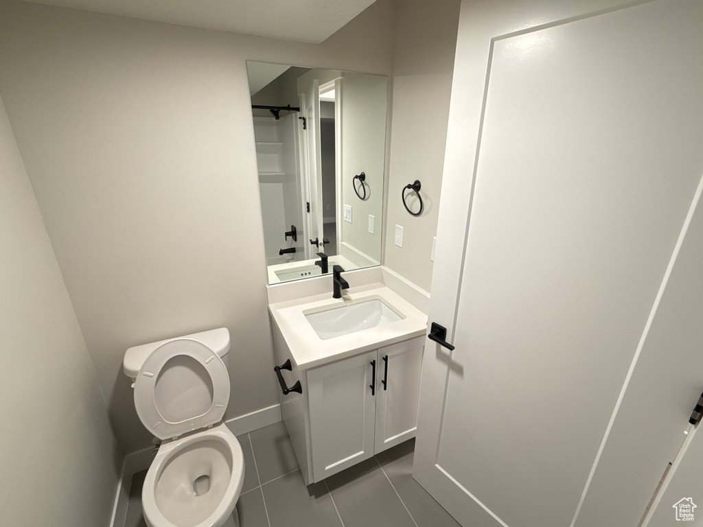 Bathroom with toilet, tile patterned floors, and vanity