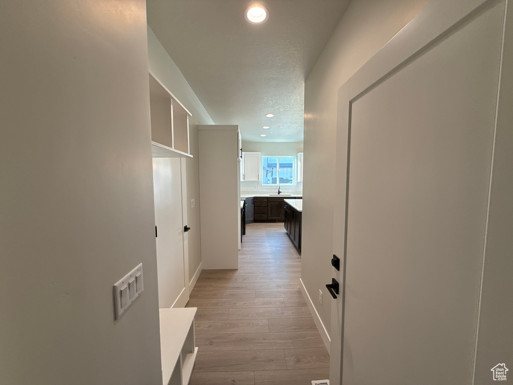 Corridor with light wood-type flooring and sink