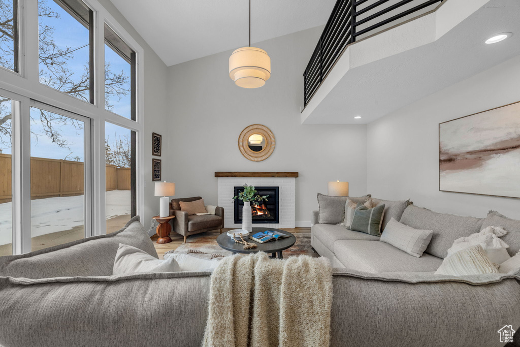 Living room featuring hardwood / wood-style floors, a towering ceiling, and a brick fireplace