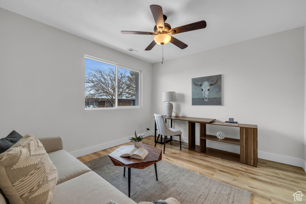 Living room with ceiling fan and light hardwood / wood-style flooring