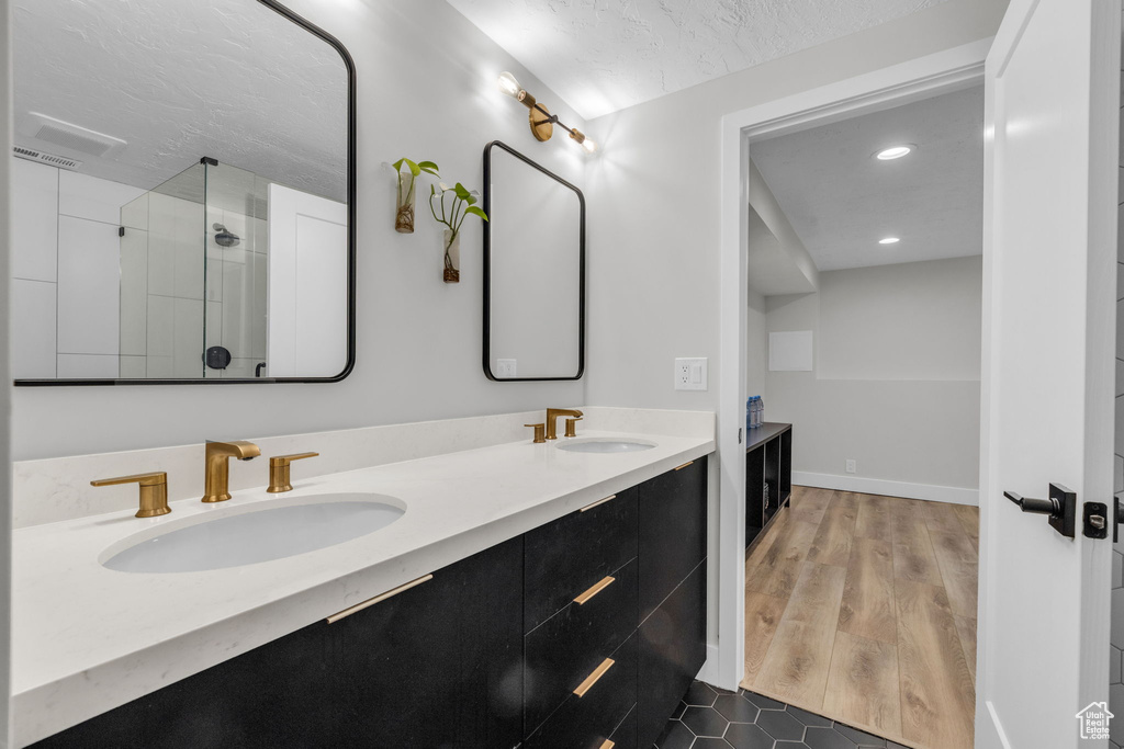 Bathroom with hardwood / wood-style flooring, a textured ceiling, walk in shower, and vanity