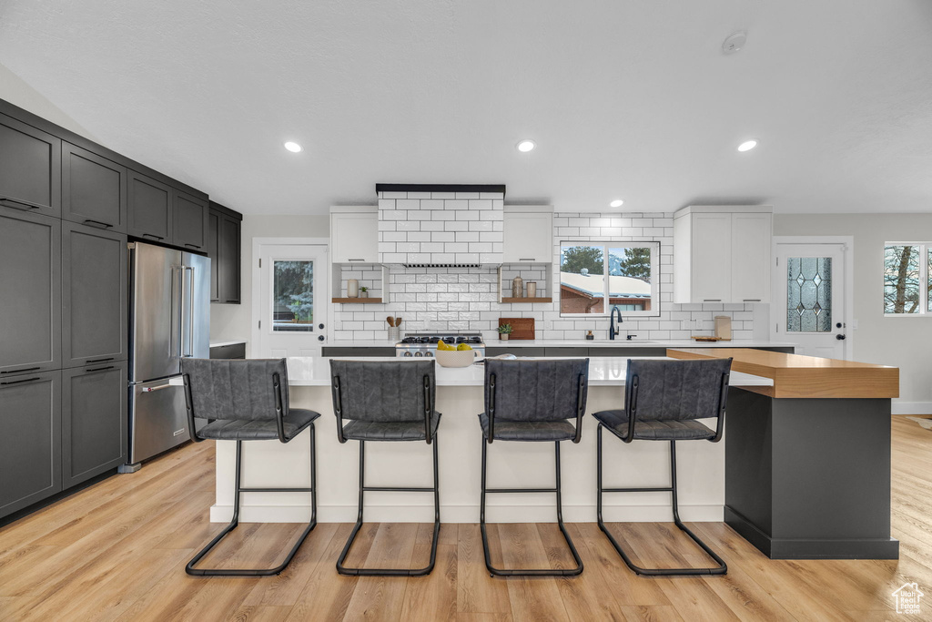Kitchen with white cabinetry, a breakfast bar, high quality fridge, and a kitchen island