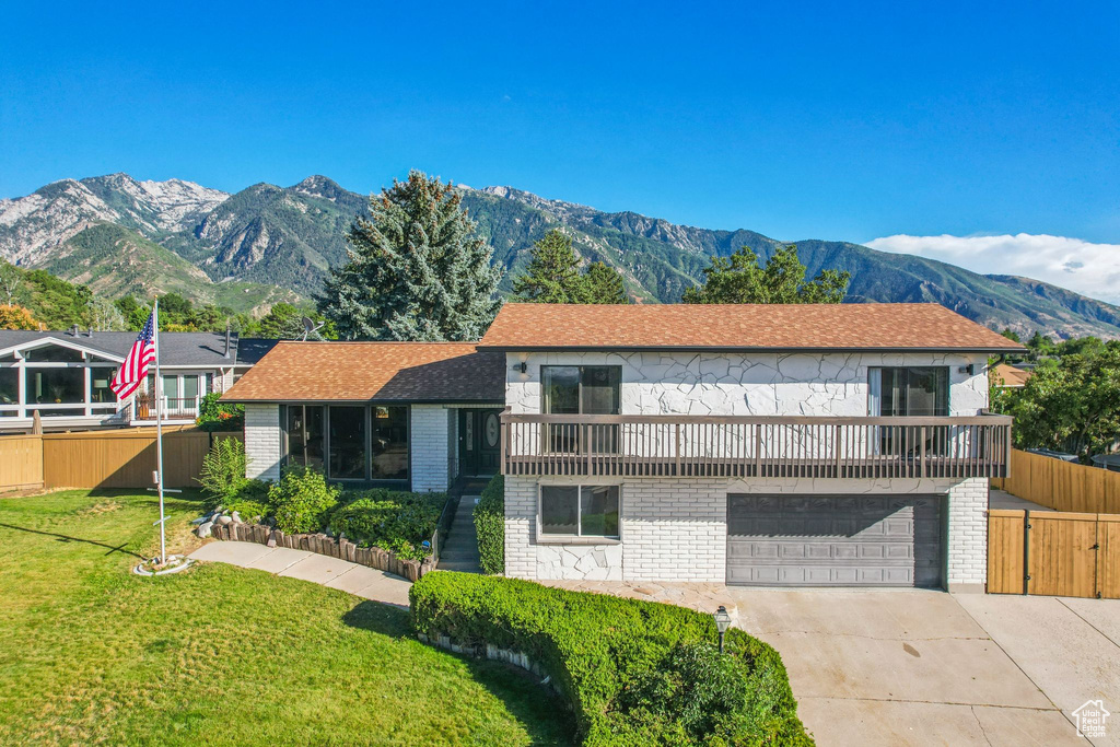 Tri-level home with a garage, fence, a front lawn, a mountain view, and driveway