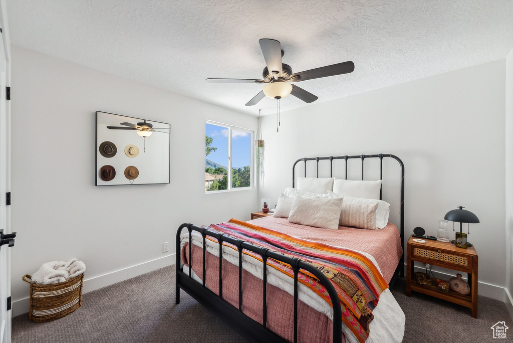 Carpeted bedroom featuring ceiling fan and a textured ceiling