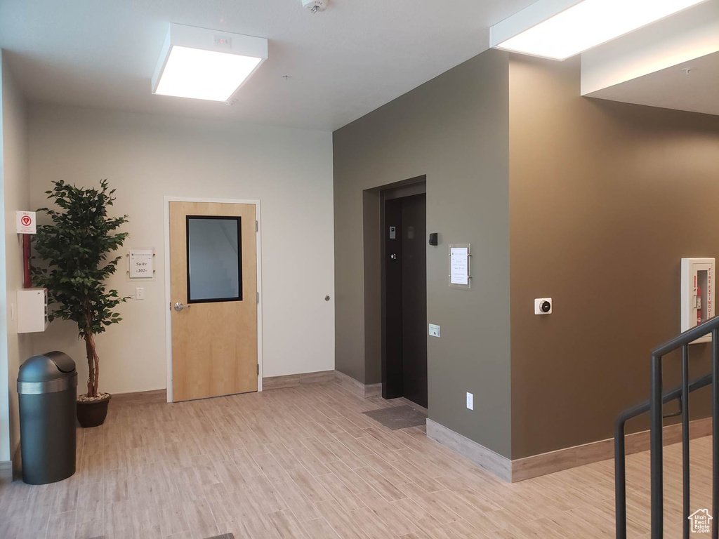 Corridor featuring light wood-type flooring and elevator