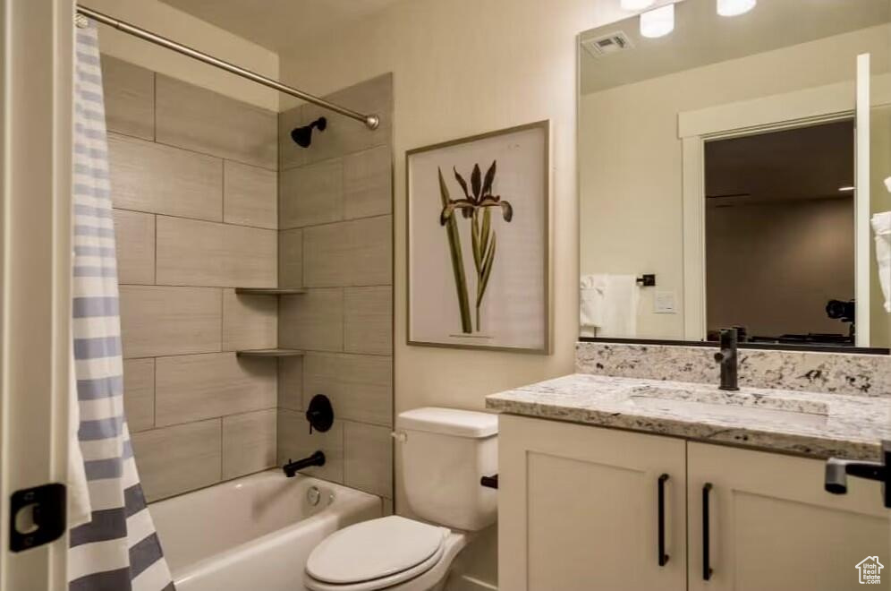Full bathroom featuring toilet, vanity, and shower / bathtub combination with curtain