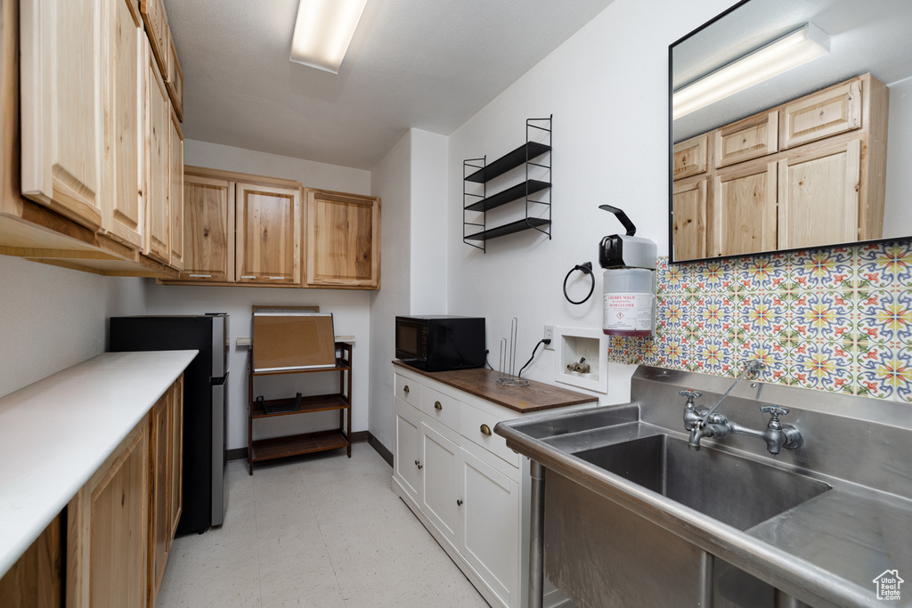 Kitchen featuring sink, stainless steel refrigerator, and light brown cabinets