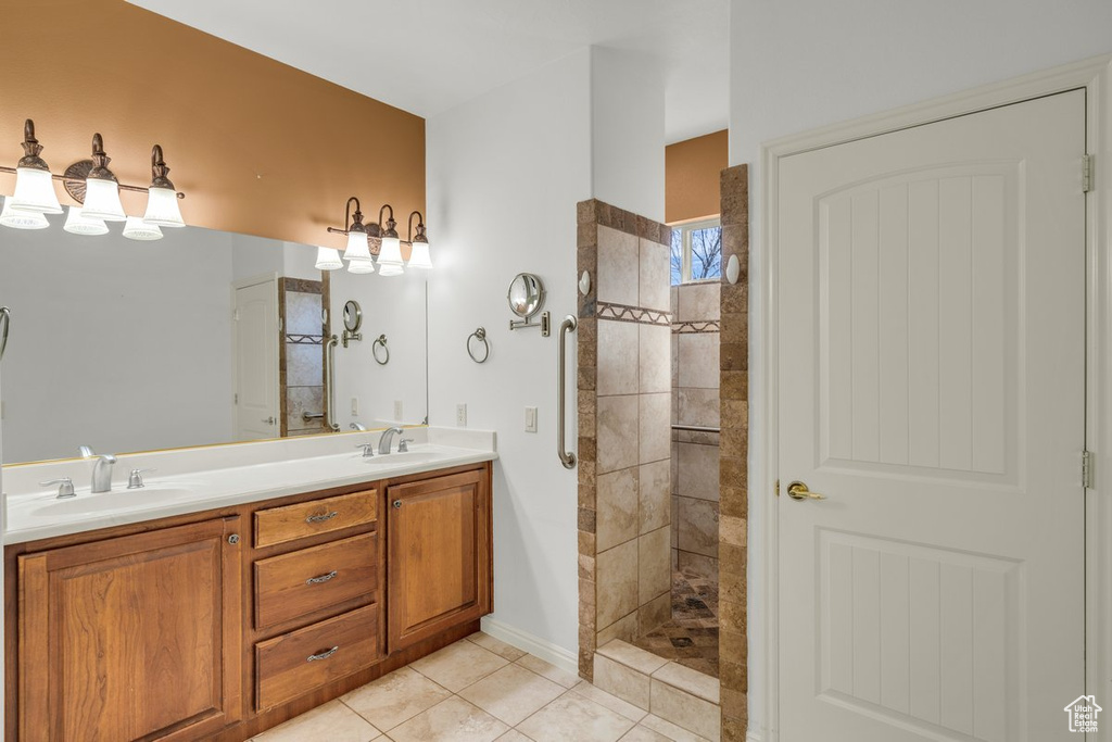 Bathroom with vanity, tile patterned flooring, and a tile shower