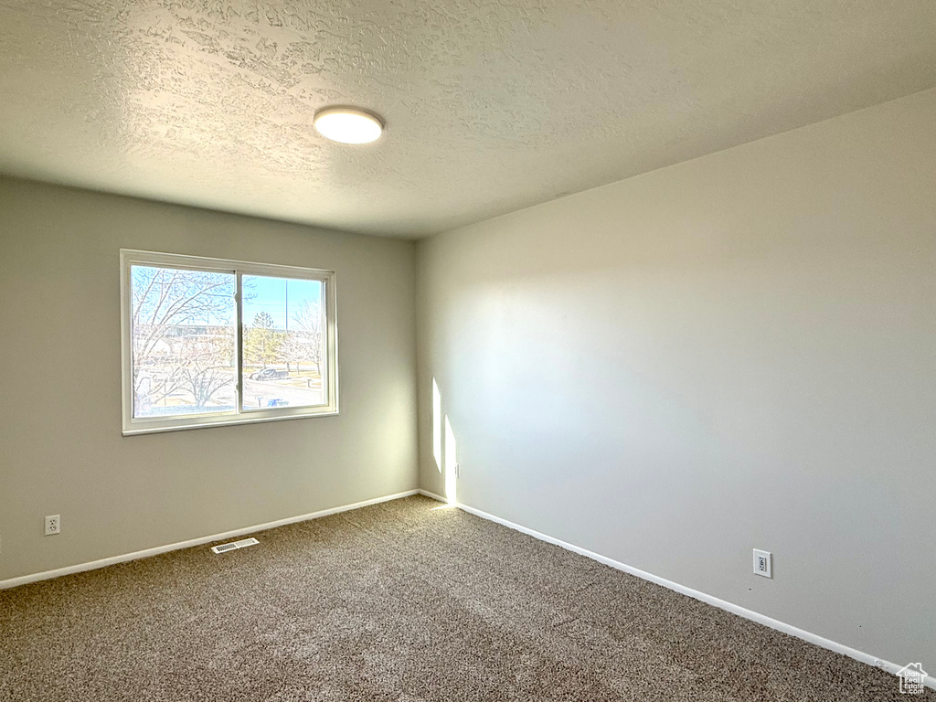 Carpeted empty room featuring a textured ceiling