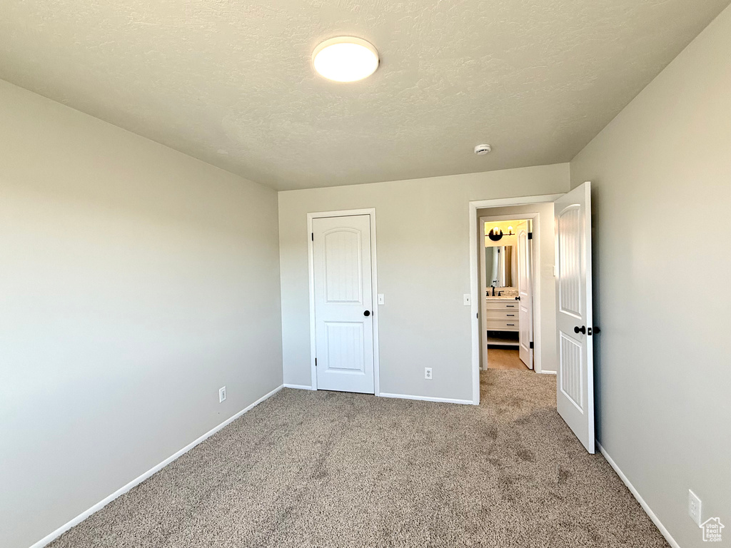 Unfurnished bedroom with a textured ceiling and carpet