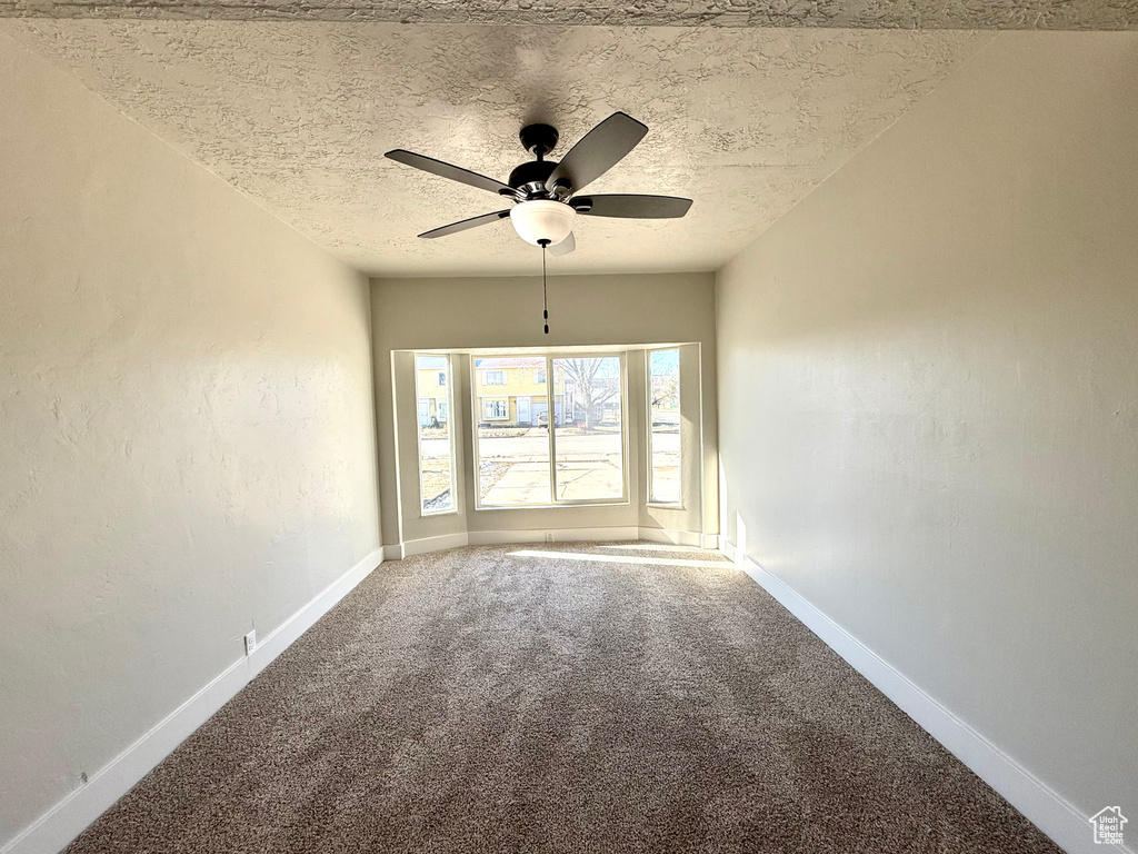 Carpeted spare room featuring ceiling fan and a textured ceiling