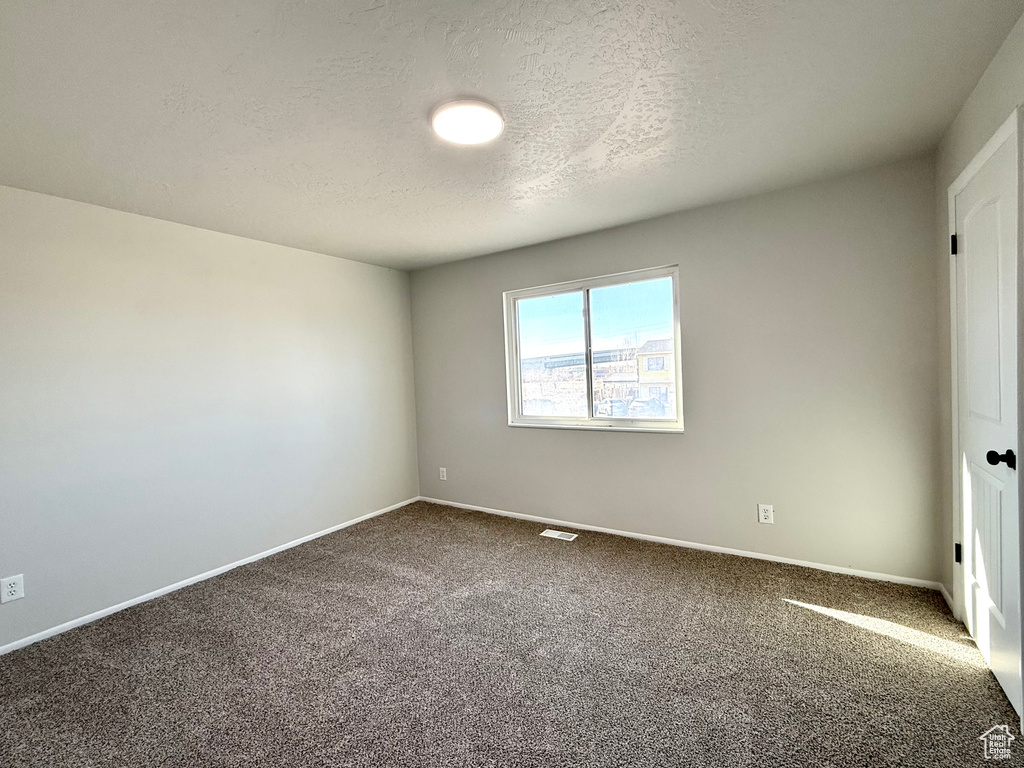 Carpeted empty room with a textured ceiling