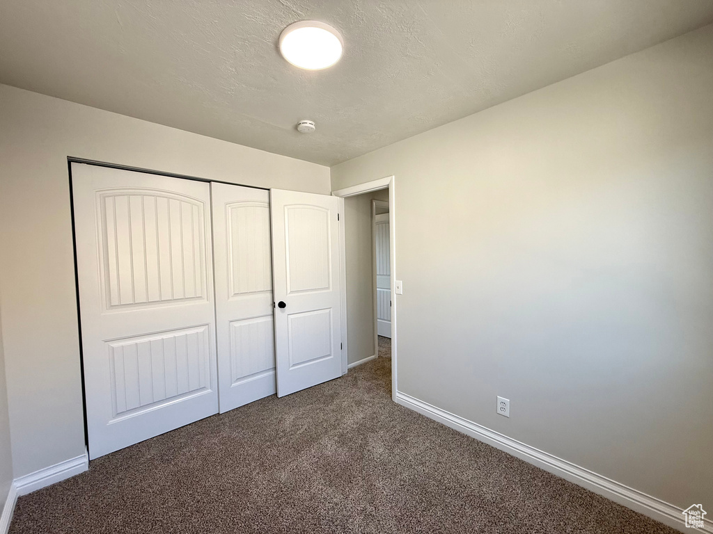 Unfurnished bedroom with a closet and dark colored carpet