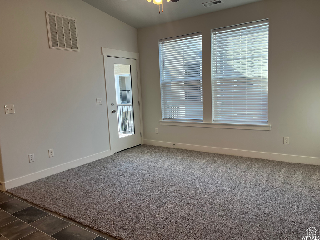 Empty room featuring ceiling fan, vaulted ceiling, and dark colored carpet