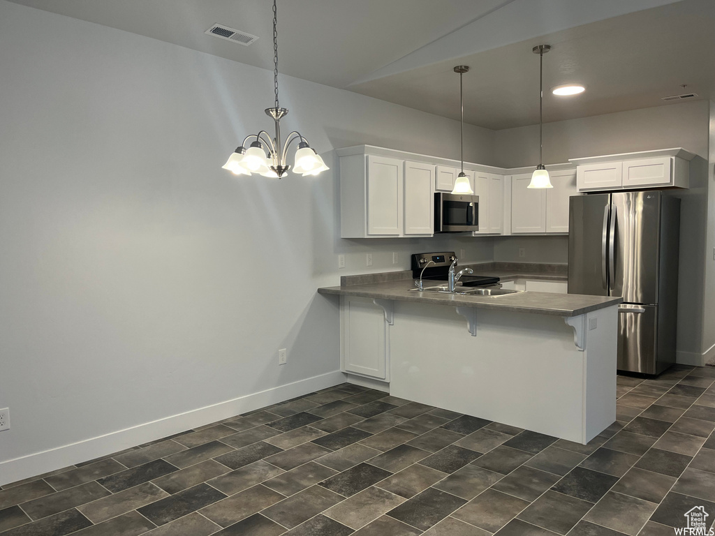 Kitchen with white cabinetry, kitchen peninsula, appliances with stainless steel finishes, a kitchen breakfast bar, and sink