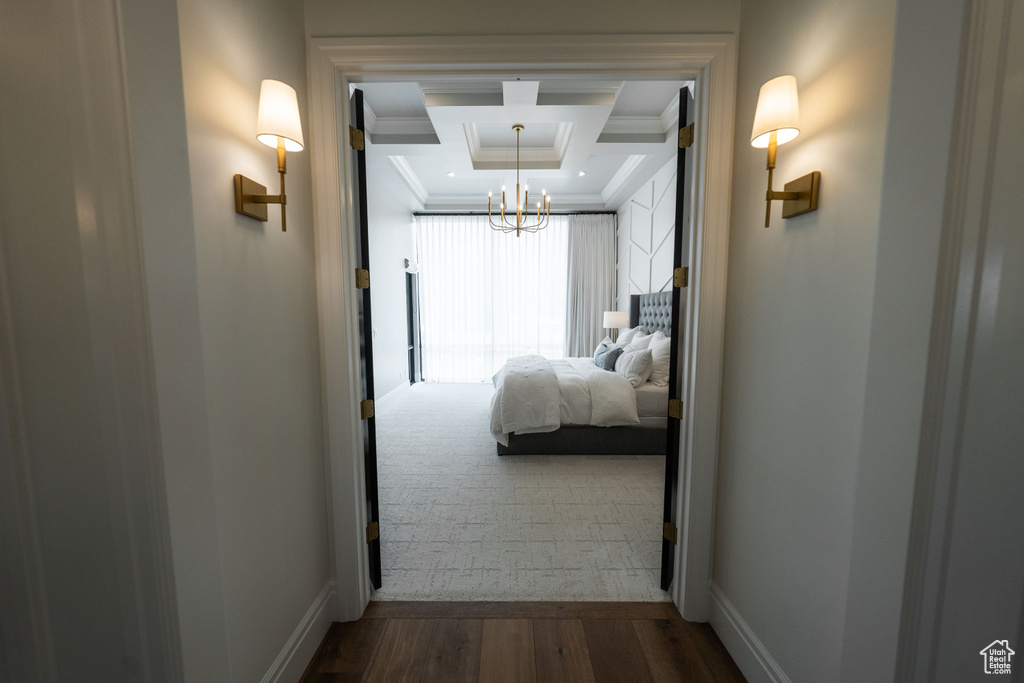 Hallway featuring ornamental molding, a chandelier, a tray ceiling, and dark wood finished floors