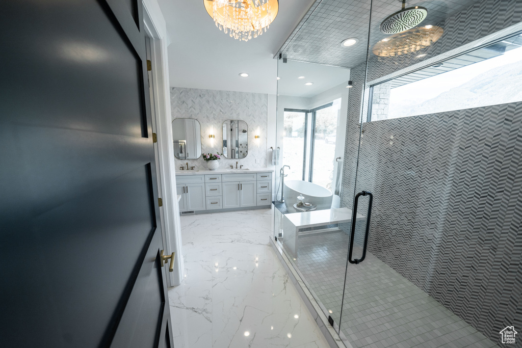 Bathroom with marble tiled floors, double vanity, a stall shower, recessed lighting, and a chandelier