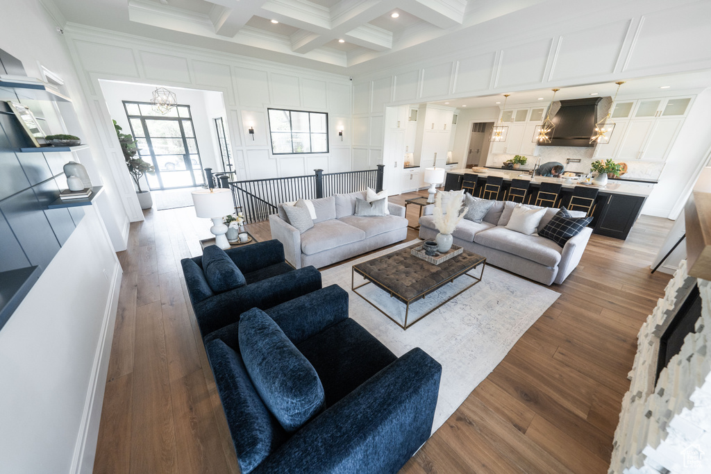 Living room featuring beamed ceiling, coffered ceiling, a high ceiling, dark wood-type flooring, and a chandelier