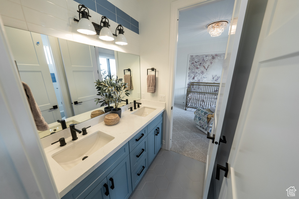 Bathroom featuring double vanity, tile patterned floors, and connected bathroom