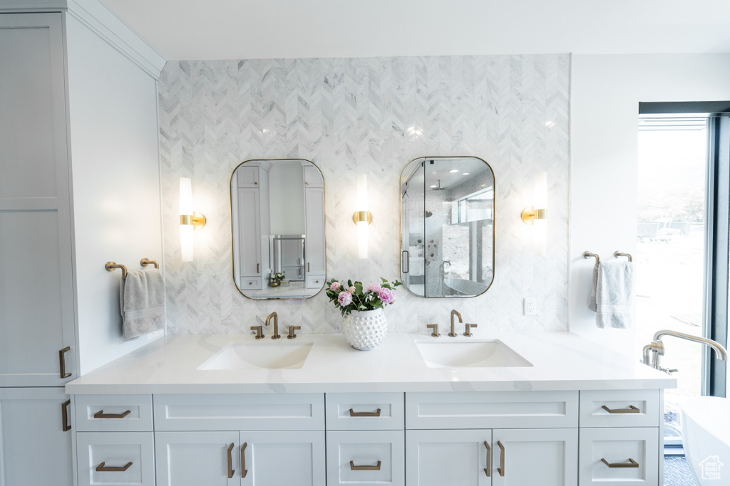 Bathroom with double vanity, tasteful backsplash, a shower with shower door, and a freestanding tub