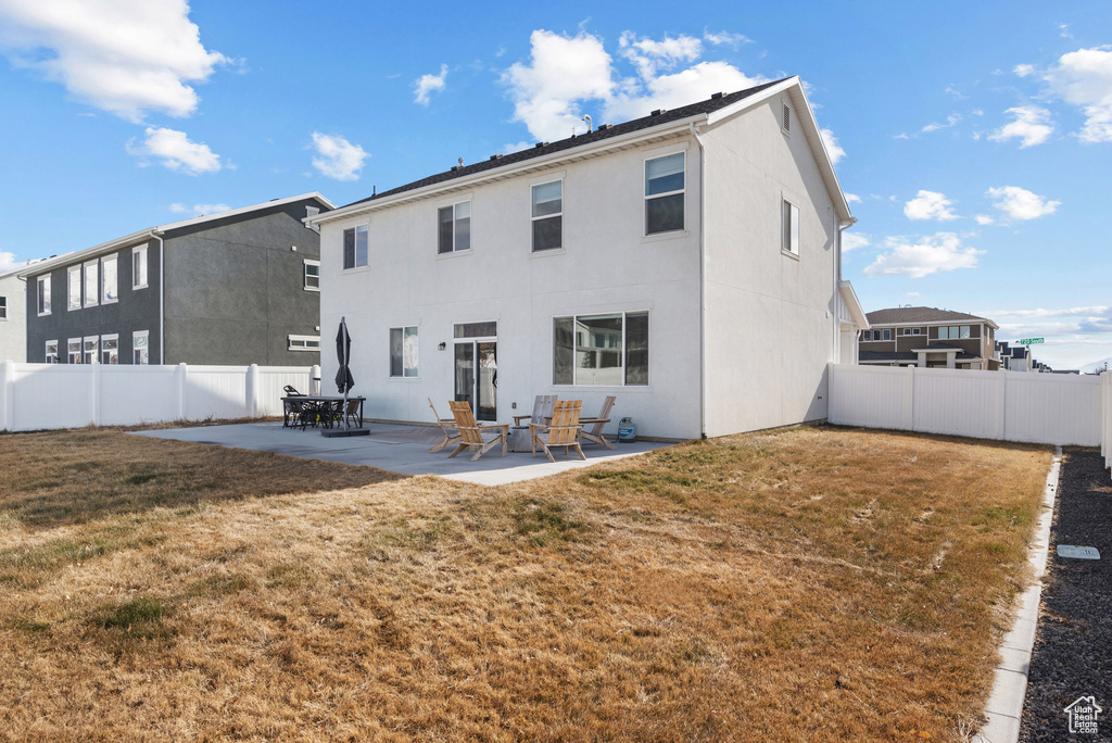 Rear view of house with a lawn and a patio