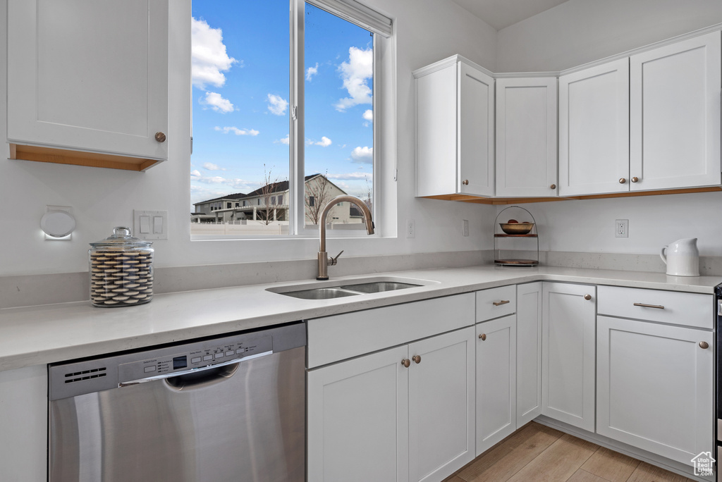 Kitchen featuring white cabinetry, light hardwood / wood-style floors, dishwasher, and sink