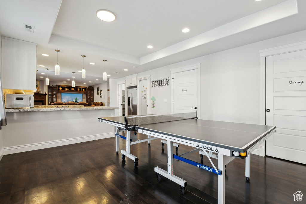 Recreation room with dark hardwood / wood-style floors and a raised ceiling