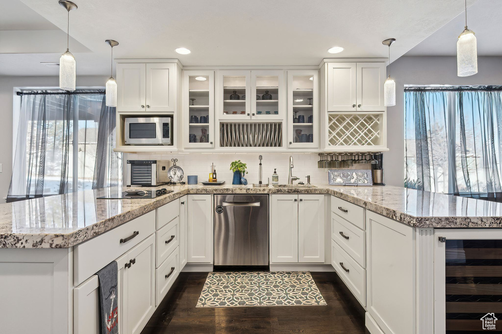 Kitchen with pendant lighting, appliances with stainless steel finishes, beverage cooler, and white cabinets