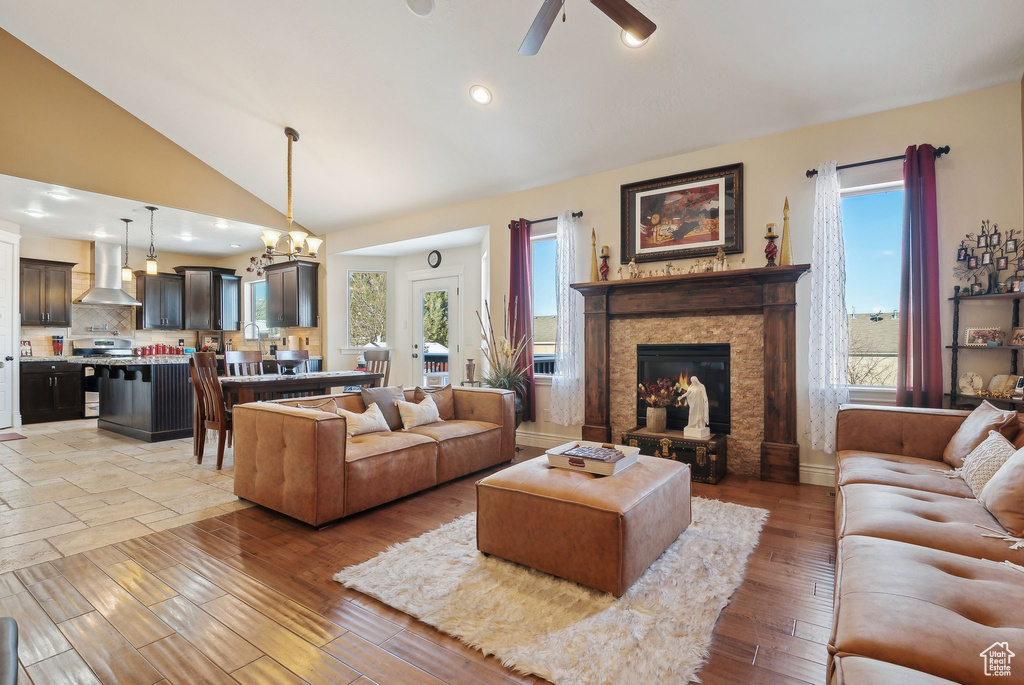 Living room featuring lofted ceiling, a fireplace, a wealth of natural light, and light hardwood / wood-style flooring