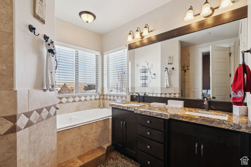 Bathroom featuring tiled tub and vanity